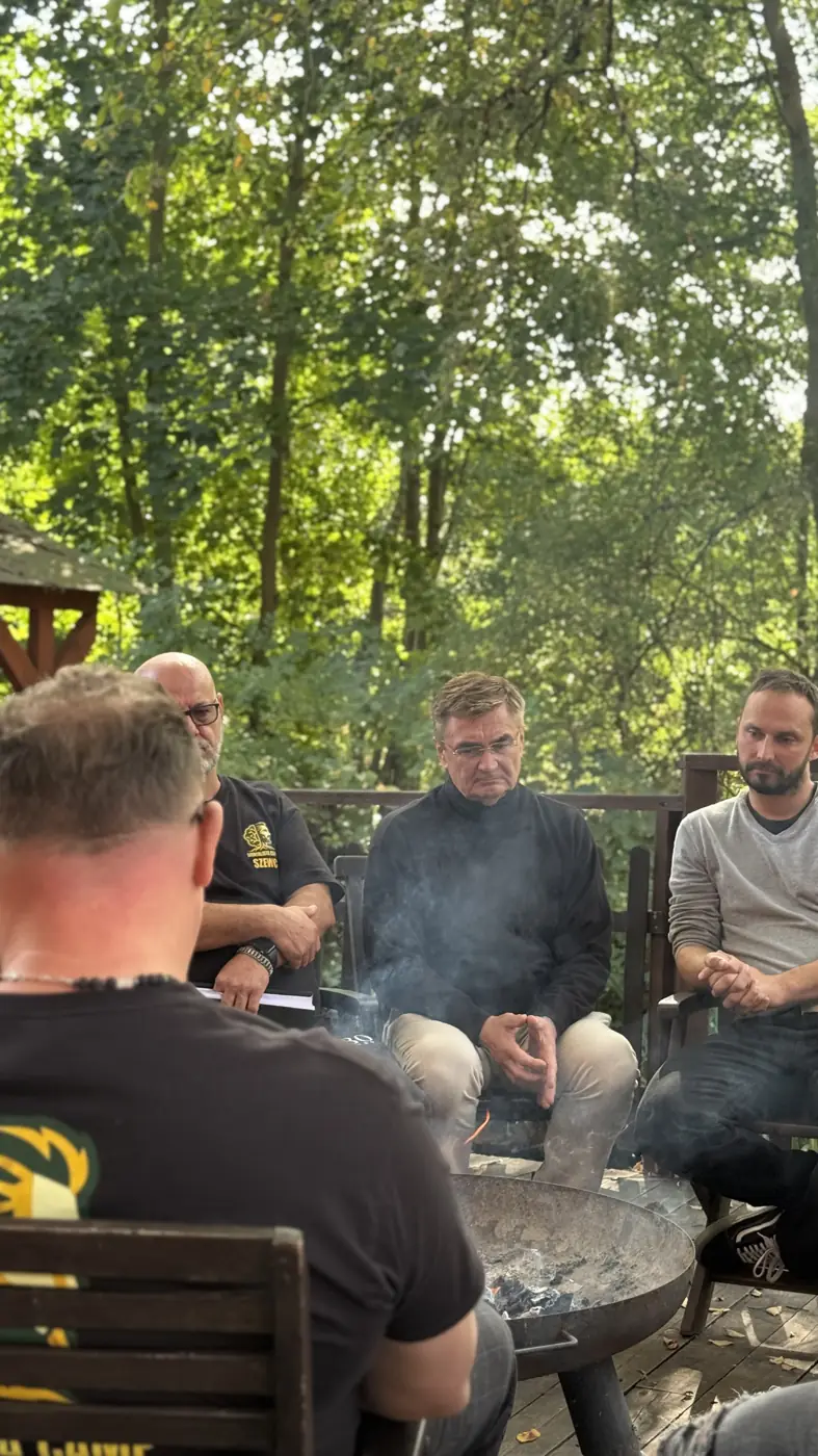 Uczestnicy siedzą w kręgu w lesie